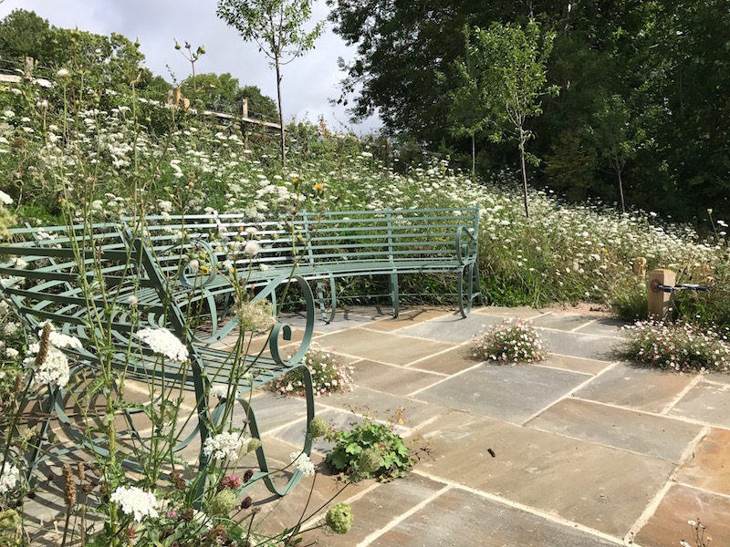 The bespoke bench set on paving and surrounded by the meadow